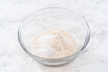 Limonlu haşhaş tohumlu kek pişirmek için bardakta çırpma kabıyla kuru malzemeyi karıştırıyorum..