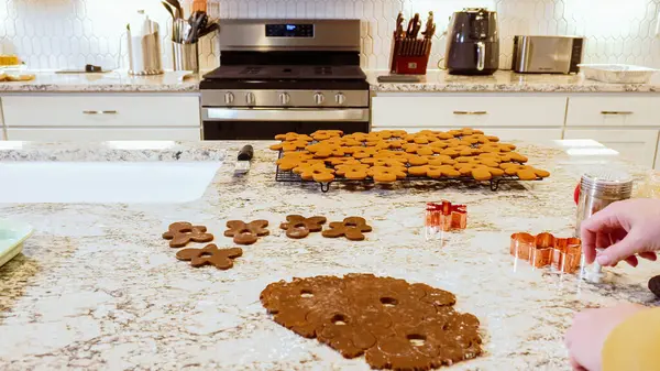さまざまなお祝いのクッキーカッターを使用して 洗練された大理石のカウンターのローリング生地から魅力的なジンジャーブレッドクッキーを切り出し 現代のキッチンに休日の応援をもたらしました — ストック写真