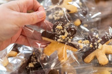 Dikkatlice paketlenmiş Noel kurabiyeleri, çikolataya batırılmış ve şeffaf selofan ambalajla sunulmuş, bayram hediyesi olarak mükemmel..