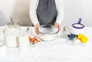 Cam kasenin içindeki malzemeleri birleştirmek, lezzetli bir vanilyalı kek hazırlamak için ustalıkla çırpmak..