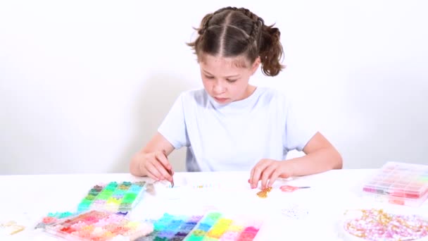 소녀는 만들기의 예술에 초점을 맞추고 독특한 패턴으로 활기찬 구슬을 스레딩 — 비디오