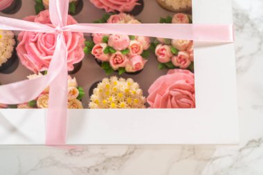 El değmemiş beyaz bir kek kutusunun içinde, her gurme kek bir sanat eseridir, tereyağı kremalı çiçeklerle süslenmiştir, canlı güllere ve lalelere benzemesi için güzelce tasarlanmıştır..