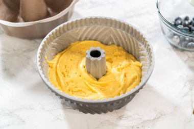 Pasta hamurunu önceden yağlanmış bohçaya nazikçe aktarmak başarılı bir pişirme işlemi için zemin hazırlıyor..