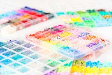 Beyaz bir masaya yerleştirilmiş çeşitli kil boncuk kutuları yaratıcı çocukların el sanatları projesini bekliyor..