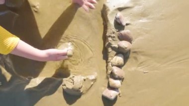 Küçük bir kız kışın soğuğu için Pismo Sahili 'nde kışın deniz kabuğu ve istiridye ararken sevinçle istiridye topluyor..