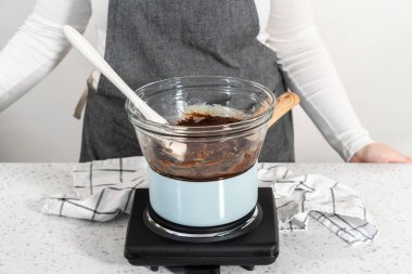 Noel kurabiyeli naneli şekerleme hazırlamak için çift katlı kazanda beyaz çikolata parçaları ve diğer malzemeler eritiliyor..