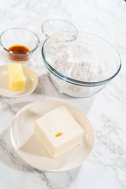 Mutfak tezgahında, krem peynirin krema tarifi için ölçülmüş malzemeler bekliyor, lezzetli ve lezzetli bir ikram vaat ediyor..