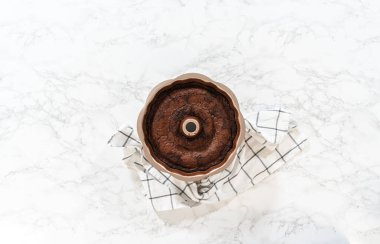 Düz yatıyordu. Chocolate Bundt Pastası dikkatlice tavadan çıkartılır. Yuvarlak soğutma rafına yerleştirilir. Kusursuz bir sunum ve hoş bir hoşgörü için hazırlanır..