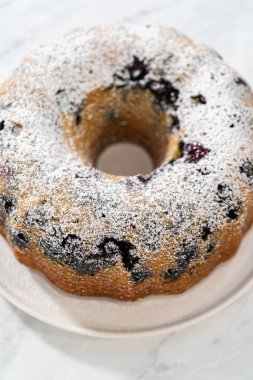 Taze fırınlanmış limonlu yaban mersinli kekin tozunu alıyorum..