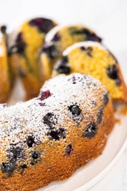 Taze pişmiş limonlu yaban mersinli kek dilimliyorum. Pudra şekerli..