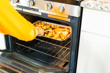 Modern bir mutfakta, yarıya indirilmiş, çok renkli mermer patatesler silikon kaplamalı bir tavaya yerleştirilir. Kızartma işlemi mutfağı ağız sulandırıcı bir aromayla dolduruyor.