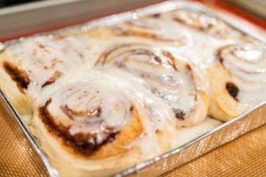 Fırından yeni çıkmış, tarçınlı çörek silikon bir hasırın üzerinde serinliyor, kremaları mutfak ışıklarının altında parlıyor..