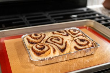 Fırından yeni çıkmış, tarçınlı çörek silikon bir hasırın üzerinde serinliyor, kremaları mutfak ışıklarının altında parlıyor..