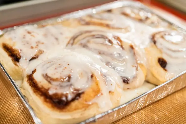 Fırından yeni çıkmış, tarçınlı çörek silikon bir hasırın üzerinde serinliyor, kremaları mutfak ışıklarının altında parlıyor..