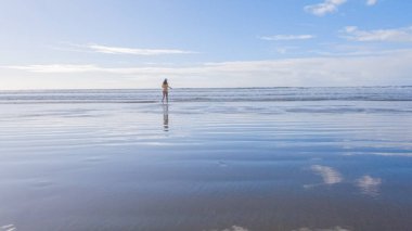 Küçük kız, soğuğa göğüs geriyor, kışın sahilde mayosuyla koşuyor..