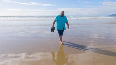 Baba ve kızı, güzel Pismo Sahili boyunca sakin ve çarpıcı dalgaların arka planında sakin bir kış yürüyüşünün keyfini çıkarıyorlar..