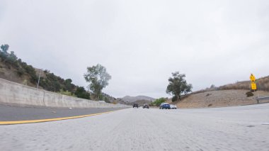 Yağmurlu bir kış gününün ortasında, Los Angeles, Kaliforniya yakınlarındaki HWY 134 'te, yağmur damlalarıyla kaplı lenslerle atmosferi yakalıyor, ve bu yolculuğa benzersiz ve dengesiz bir perspektif ekliyor..