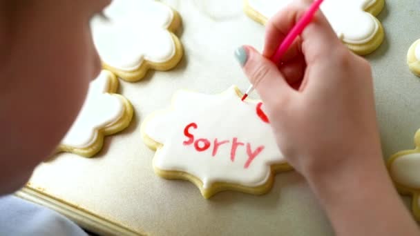 一个小女孩细心地写下了一个感人的场景 在糖饼干上涂上了食物的颜色 饼干上撒满了白色的皇家糖霜 真叫人难过 — 图库视频影像