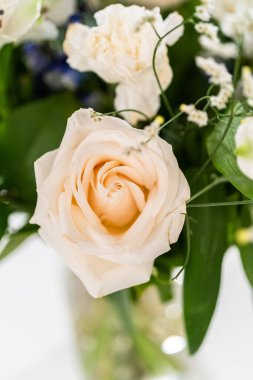 Taze beyaz güllerin ve çeşitli çiçeklerin bulunduğu büyüleyici bir buket, zarif bir vazoda düzenlenmiş, zamansız bir güzellik yayıyor..