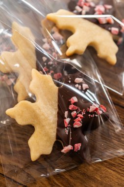 Dikkatlice paketlenmiş Noel kurabiyeleri, çikolataya batırılmış ve şeffaf selofan ambalajla sunulmuş, bayram hediyesi olarak mükemmel..