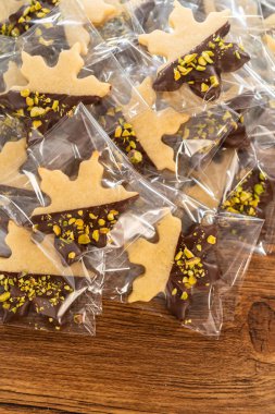 Dikkatlice paketlenmiş Noel kurabiyeleri, çikolataya batırılmış ve şeffaf selofan ambalajla sunulmuş, bayram hediyesi olarak mükemmel..