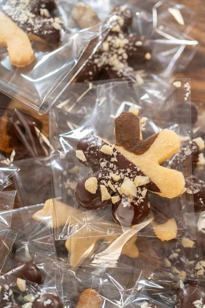 Dikkatlice paketlenmiş Noel kurabiyeleri, çikolataya batırılmış ve şeffaf selofan ambalajla sunulmuş, bayram hediyesi olarak mükemmel..