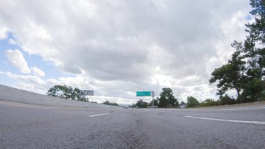 Bulutlu bir kış gününde, bir araba, Santa Maria, California yakınlarındaki 101. Otoyol boyunca bulutlu bir gökyüzünün altında, yeşil ve altın renkli bir karışımla sorunsuzca yol alır..