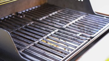 Açık hava ortamında, iki ocaklı ızgara pişirme başlamadan önce dikkatli bir bakım görüyor. Izgara titizlikle özel bir ızgara fırçasıyla temizlenmiş.