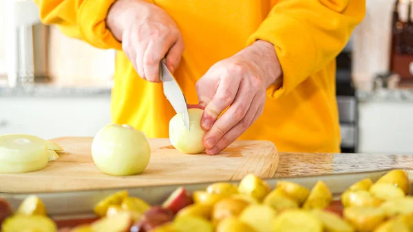 現代的なキッチンの歓迎の場で 若い男は夕食の準備プロセスを続けています リングに黄色の玉ねぎをスライスすることに携わっているHesは Aにグリルするためにそれらをプレッピング — ストック写真