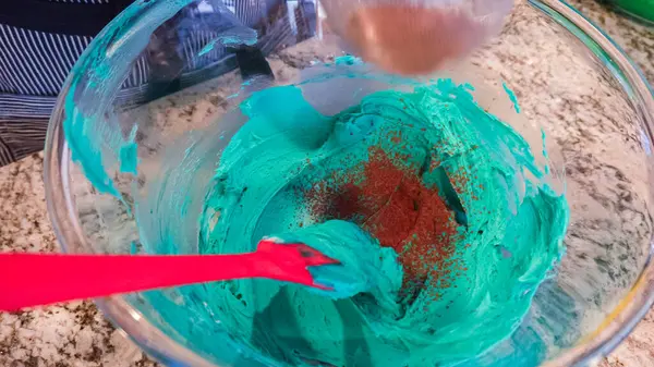 İyi ışıklandırılmış bir mutfakta, yeşil ve diğer renklerin çeşitli tonlarında tereyağlı krema çeşitleri büyüleyici kapkeklerin sanatsal dekorasyonu için titizlikle karıştırılıyor ve hazırlanıyor.