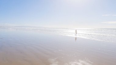 Küçük kız, soğuğa göğüs geriyor, kışın sahilde mayosuyla koşuyor..