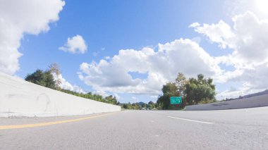 Açık bir kış gününde, bir araba, Santa Maria, California yakınlarındaki 101. Otoyol boyunca yeşil ve altın renkli bir karışımla çevrili, parlak mavi bir gökyüzünün altında sorunsuzca seyahat eder..
