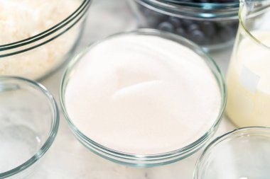 Limonlu yaban mersinli kek pişirmek için bardakların içindeki ölçülü malzemeler..