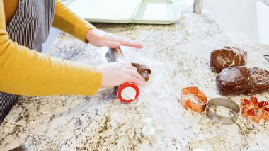 Modern bir mutfaktaki zarif mermer tezgahın üzerine zencefilli kurabiye hamuru sermek için ayarlanabilir bir merdane kullanmak, bayram pişirme şenliğine hazırlanmak....