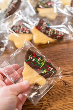 Dikkatlice paketlenmiş Noel kurabiyeleri, çikolataya batırılmış ve şeffaf selofan ambalajla sunulmuş, bayram hediyesi olarak mükemmel..
