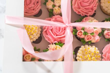 El değmemiş beyaz bir kek kutusunun içinde, her gurme kek bir sanat eseridir, tereyağı kremalı çiçeklerle süslenmiştir, canlı güllere ve lalelere benzemesi için güzelce tasarlanmıştır..