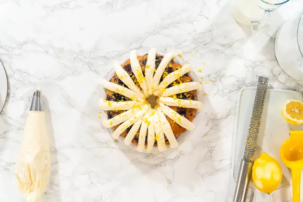 Flat lay. The final stage of this delightful baking journey involves artistically piping the silky cream cheese buttercream frosting atop the cooled bundt cakes, creating an irresistible treat.