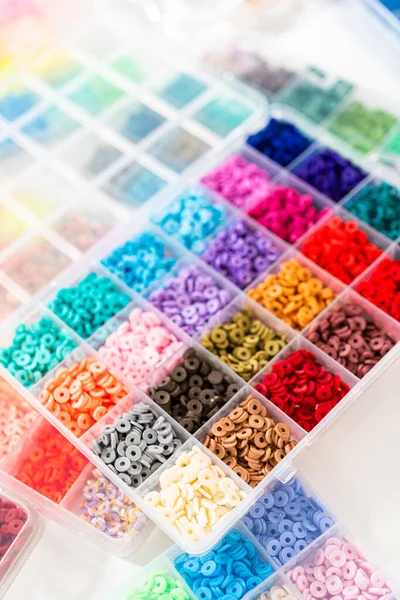 Beyaz bir masaya yerleştirilmiş çeşitli kil boncuk kutuları yaratıcı çocukların el sanatları projesini bekliyor..