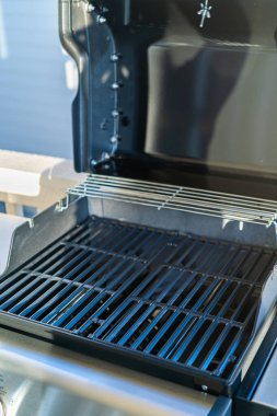 Yakından bakıldığında, banliyödeki bir evin balkonunda ilk açık hava yemek pişirme macerasını bekleyen iki ocaklı ızgaranın bozulmamış ızgarasını gösteriyor..