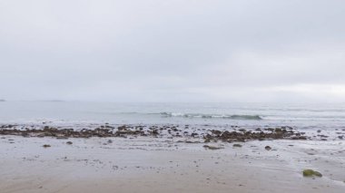 Kaliforniya, Miramar Sahili kıyılarında yürürken bulutlu kış gökyüzü sakin ve yansıtıcı bir atmosfer yaratır..
