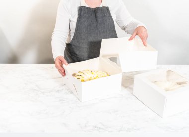 Taze pişmiş kekler beyaz kağıt kutulara dikkatlice yerleştirilir ve lezzetli görünümlerini korurken onları güvenli bir şekilde ulaşıma hazırlarlar..