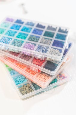 Beyaz bir masaya yerleştirilmiş çeşitli kil boncuk kutuları yaratıcı çocukların el sanatları projesini bekliyor..