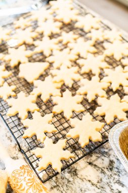 Lezzetli kar tanesi şekilli şekerli kurabiyeleri rafta soğutup onları Noel hediyelerine hazırlıyorum..