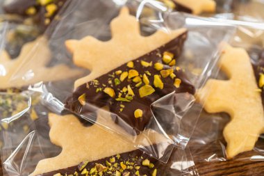 Dikkatlice paketlenmiş Noel kurabiyeleri, çikolataya batırılmış ve şeffaf selofan ambalajla sunulmuş, bayram hediyesi olarak mükemmel..