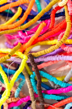 Beyaz bir masadaki renklere göre düzenlenmiş canlı bir kil boncuk koleksiyonu genç zanaatkarlara kendi eşsiz bileziklerini yapmaları için ilham vermeye hazır..