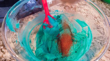 İyi ışıklandırılmış bir mutfakta, yeşil ve diğer renklerin çeşitli tonlarında tereyağlı krema çeşitleri büyüleyici kapkeklerin sanatsal dekorasyonu için titizlikle karıştırılıyor ve hazırlanıyor.