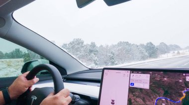 Denver, Colorado, ABD-7 Aralık 2022 bir Tesla elektrikli arabasıyla, bir sürücü kış fırtınası sırasında Batı Coloradoslar 'ın karlı arazilerinde doğru düzgün yol alır..