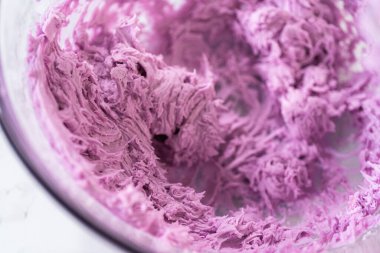 Eldeki görev, taze pişmiş vanilyalı ve çikolatalı keklerin üzerine ustalıkla borulamak üzere lezzetli bir krema kreması yapmak..