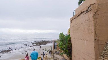 Los Angeles, California, ABD-4 Aralık 2022-POV-Yürürken Miramar Sahili, California kıyılarında bulutlu kış gökyüzü sakin ve yansıtıcı bir atmosfer yaratır..