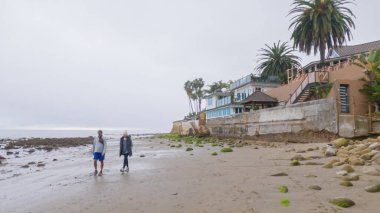 Los Angeles, California, ABD-4 Aralık 2022-POV-Yürürken Miramar Sahili, California kıyılarında bulutlu kış gökyüzü sakin ve yansıtıcı bir atmosfer yaratır..